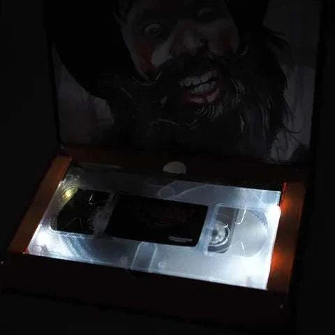 Limited Edition Deluxe LED VHS of "Cannibal! The Musical" in open box with glowing LED lights.